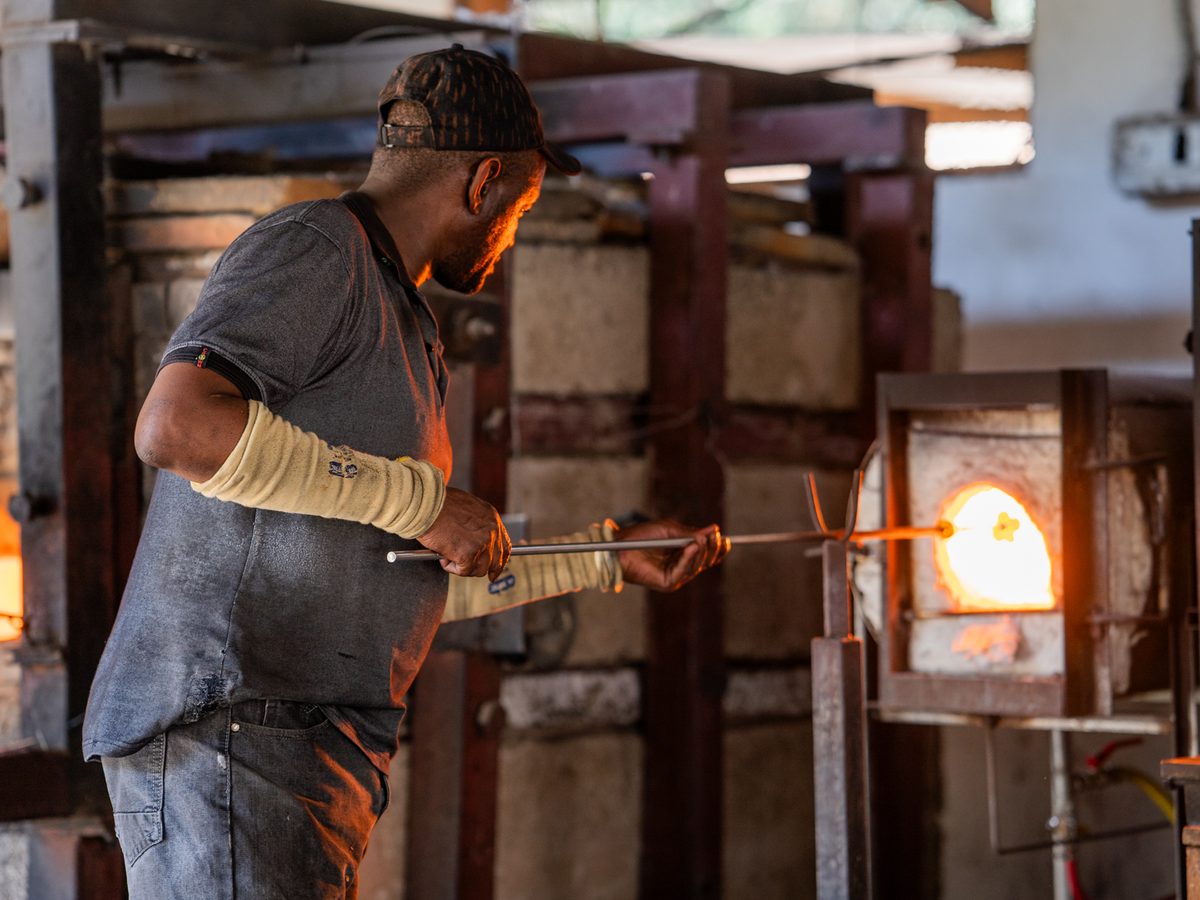 A glass-blower shaping molten glass at the furnace