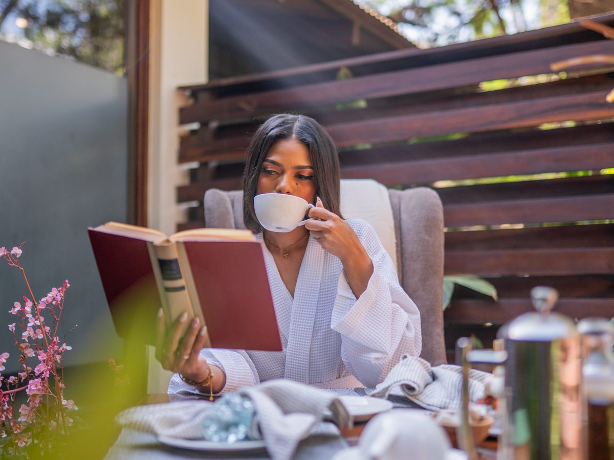 A guest in a robe with tea on a private deck